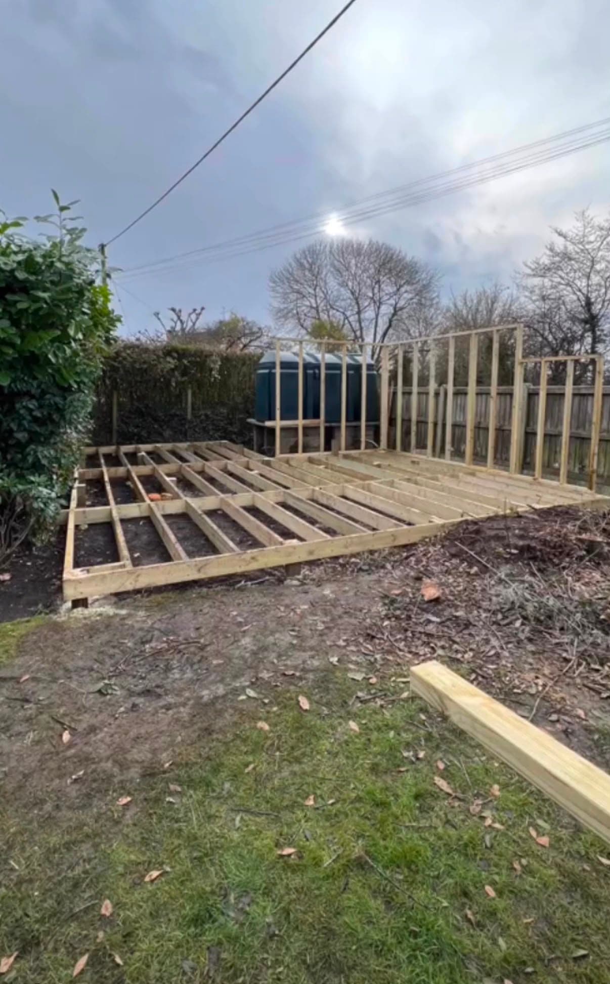 the winter shot — bare joists on soil, stud frame going up around the blue oil tank